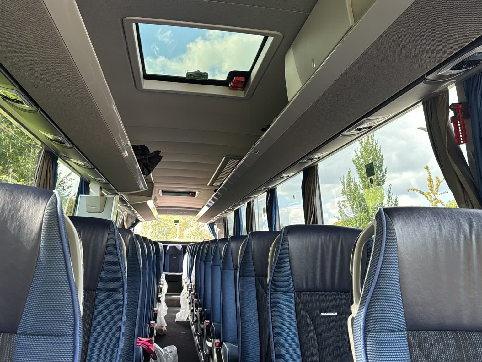 Innenraum des Fernreisebusses mit Panorama-Dachluke und Reisesitzen